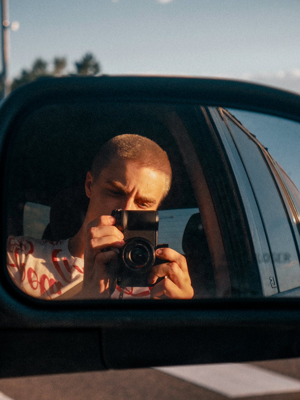 a man takes a photo reflection of a vehicle side mirror